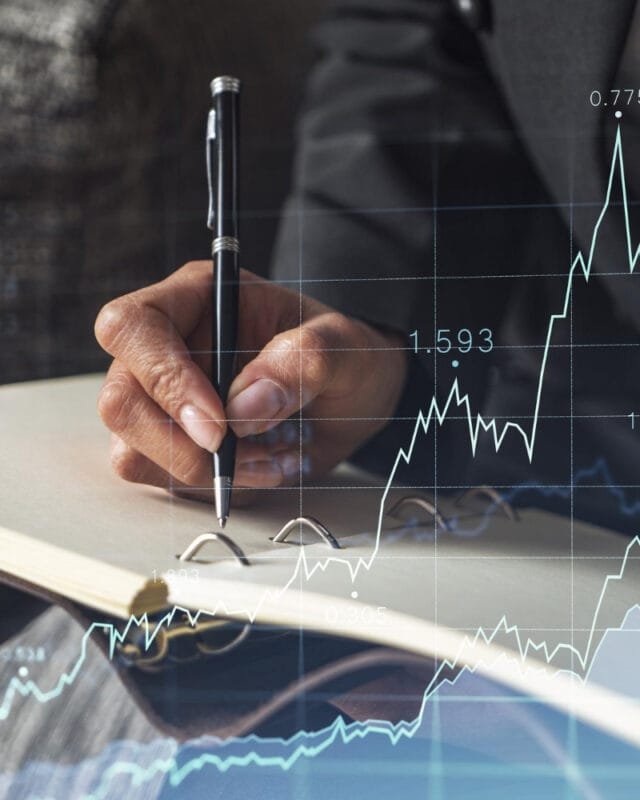 A person in a suit writing Asian M&A Investment Strategies in a notebook, overlaid with financial graphs and data, symbolizing investment and analysis.