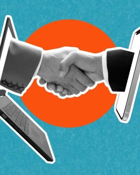 A handshake emerges between a laptop and a smartphone, symbolizing digital connection and collaboration against a vibrant blue background.