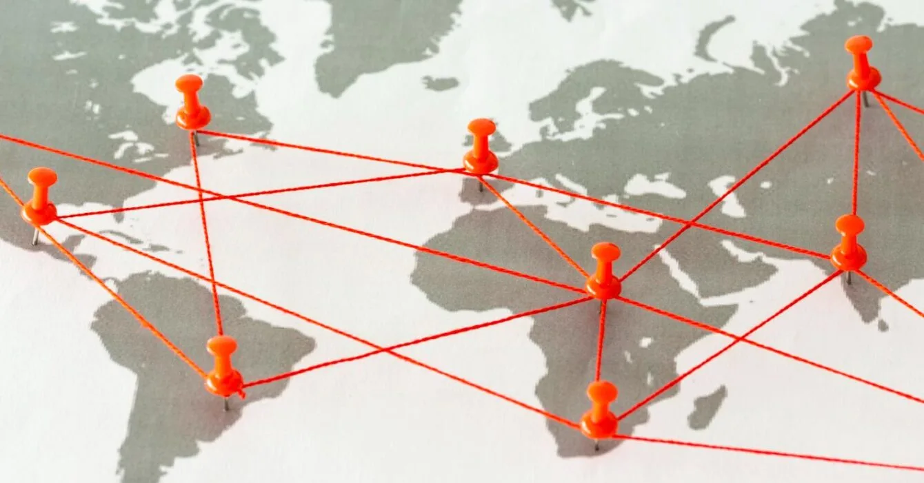 9525288 A world map with orange pushpins connected by red lines, illustrating global connections and networks.