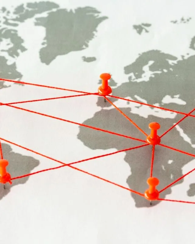9525288 A world map with orange pushpins connected by red lines, illustrating global connections and networks.