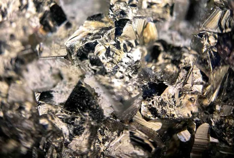 Asia M&A Rare-Earth Momentum: Close-up of reflective, jagged crystals, showcasing a mix of metallic silver and black hues with sharp angles and intricate textures.