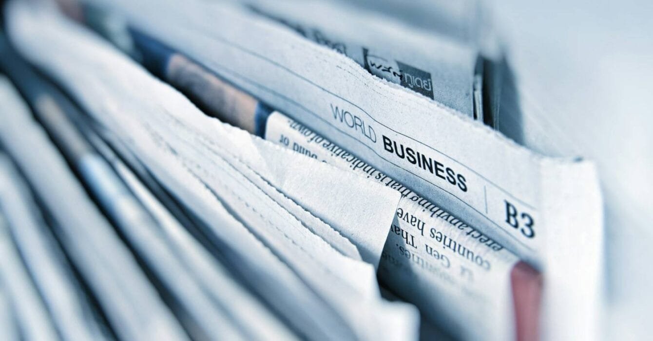Asia M&A Private Equity Resilience: Close-up of stacked newspapers, prominently displaying the headline "World Business" on the top page.