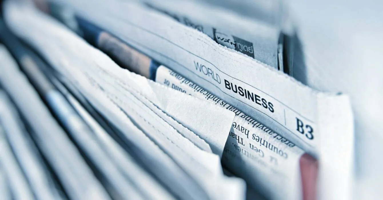 Asia M&A Private Equity Resilience: Close-up of stacked newspapers, prominently displaying the headline "World Business" on the top page.
