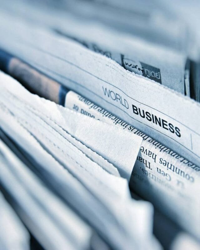 Asia M&A Private Equity Resilience: Close-up of stacked newspapers, prominently displaying the headline "World Business" on the top page.